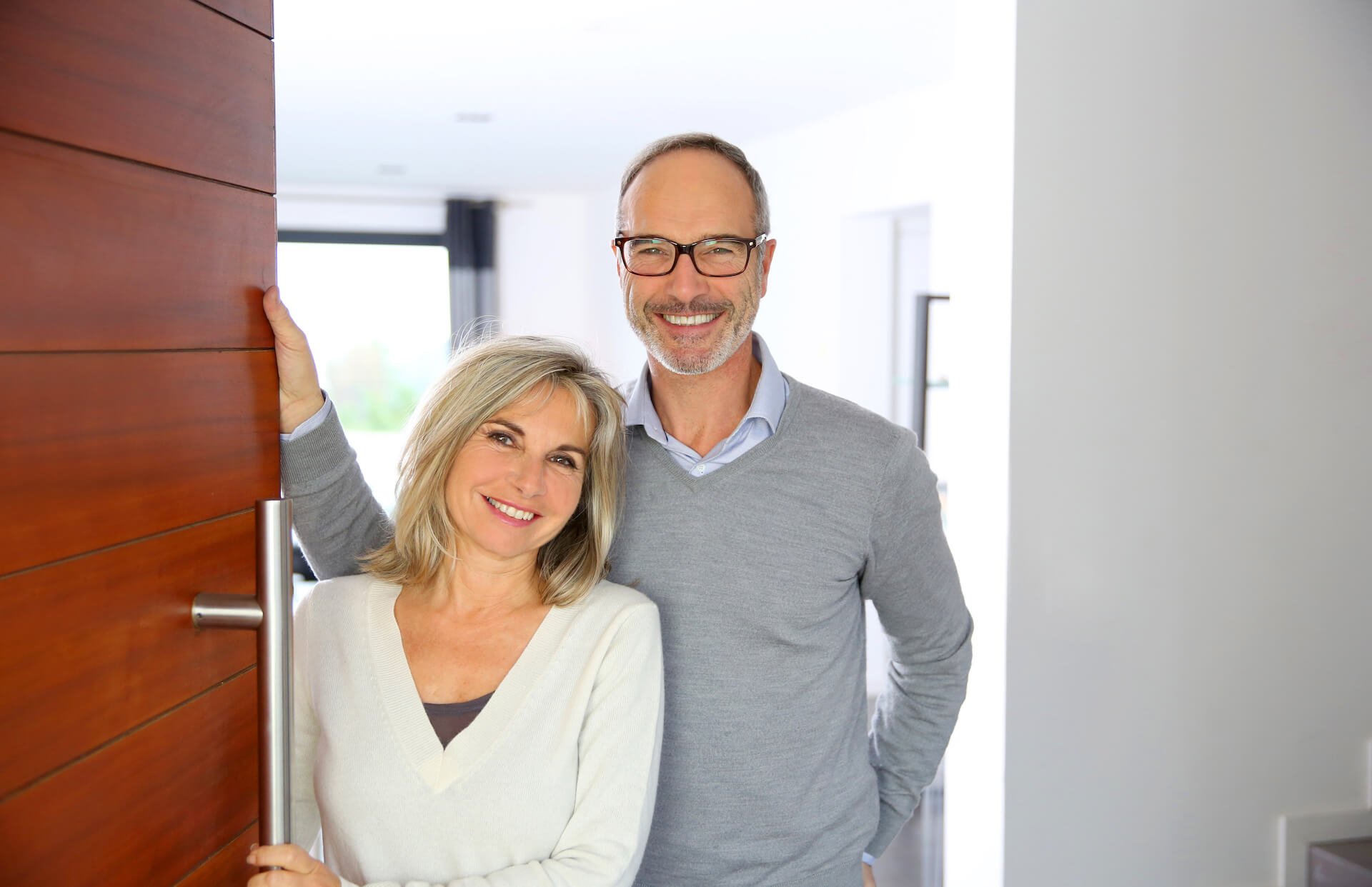 Man and woman smiling at their front door